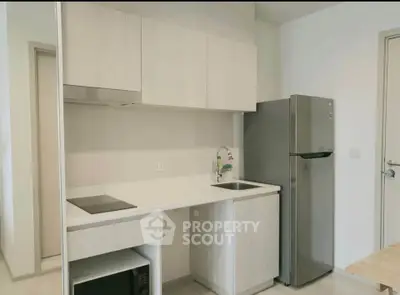 Modern kitchen with sleek cabinetry and stainless steel fridge in a compact layout.