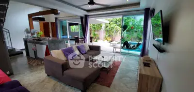 Spacious living room with open layout, modern kitchen, and poolside view, perfect for entertaining.