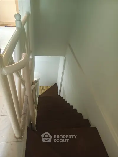 Charming staircase with wooden steps and white railing in a cozy home setting.