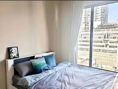 Bright bedroom with large window offering city view, modern decor and cozy bedding.