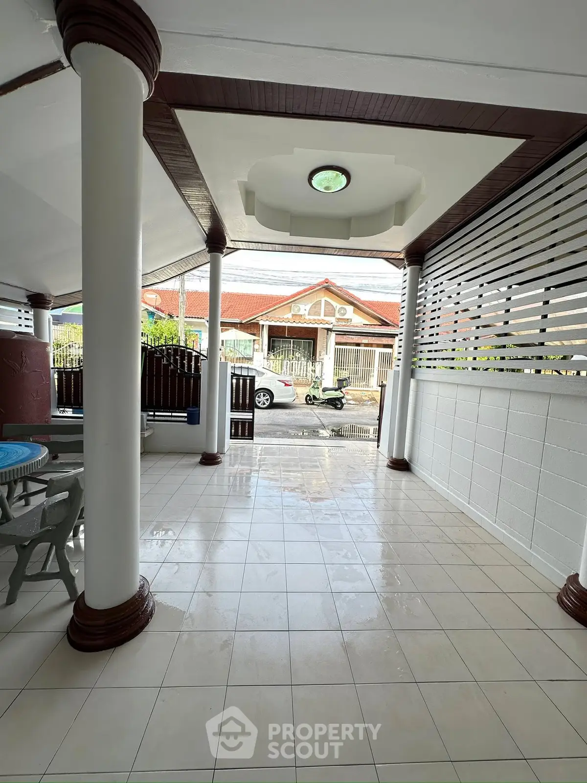 Charming covered patio with elegant columns and tiled flooring, perfect for outdoor relaxation.
