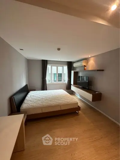 Spacious modern bedroom with large window and stylish furniture in a contemporary apartment.