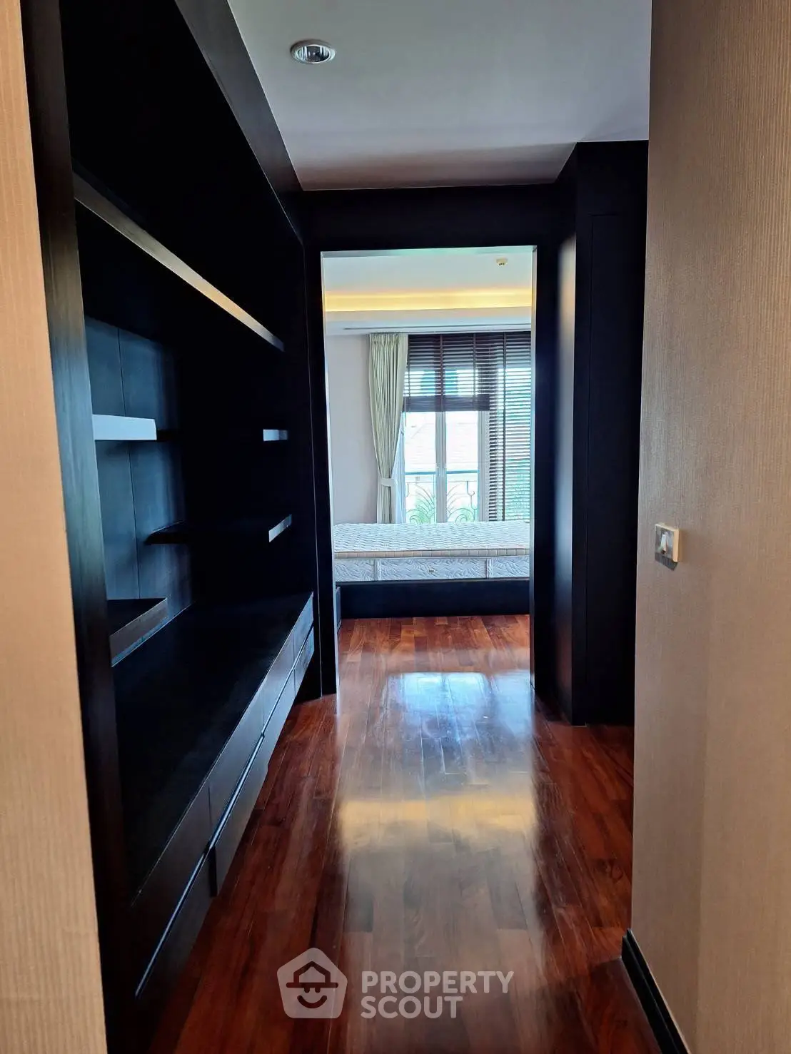 Luxurious hallway leading to a sunlit bedroom with elegant wooden flooring and modern design.