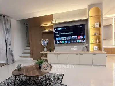 Modern living room with stylish decor and large TV, featuring elegant shelving and cozy seating area.