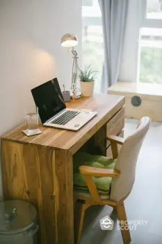 Cozy home office with wooden desk, laptop, and natural light