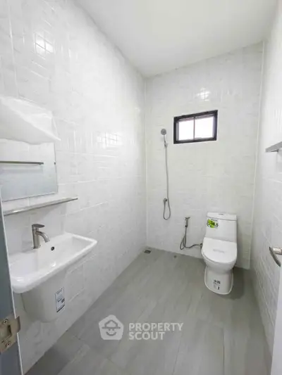 Modern minimalist bathroom with white tiles and sleek fixtures.