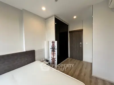 Modern bedroom with sleek design and wooden flooring, featuring a large wardrobe and ambient lighting.