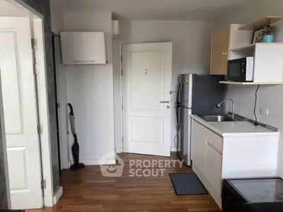 Compact kitchen with modern appliances and wooden flooring in cozy apartment.