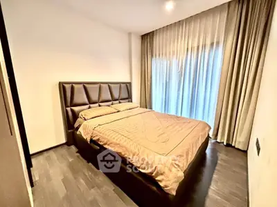 Modern bedroom with elegant decor and large window draped with curtains, featuring a comfortable bed and stylish flooring.