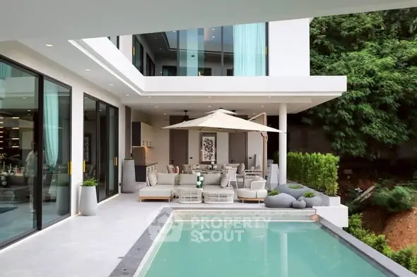 Luxurious modern home with poolside patio and stylish outdoor seating area.