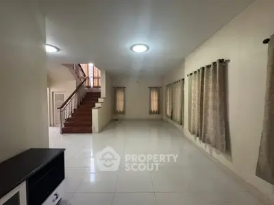 Spacious empty living room with staircase and tiled flooring