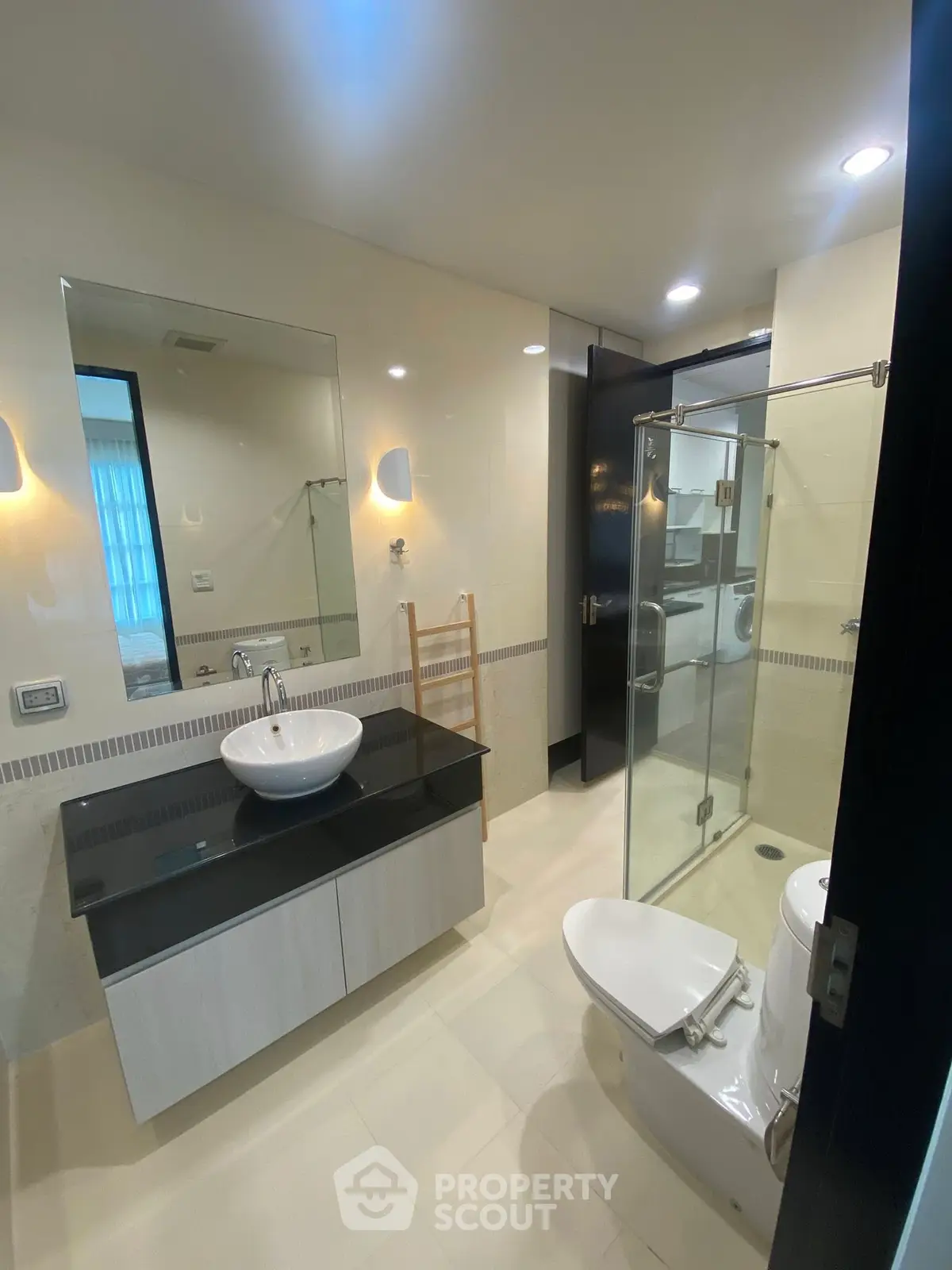 Modern bathroom with glass shower and sleek vanity in luxury apartment.