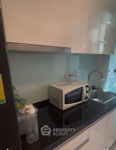 Modern kitchen with sleek cabinets, microwave, and sink, perfect for urban living.