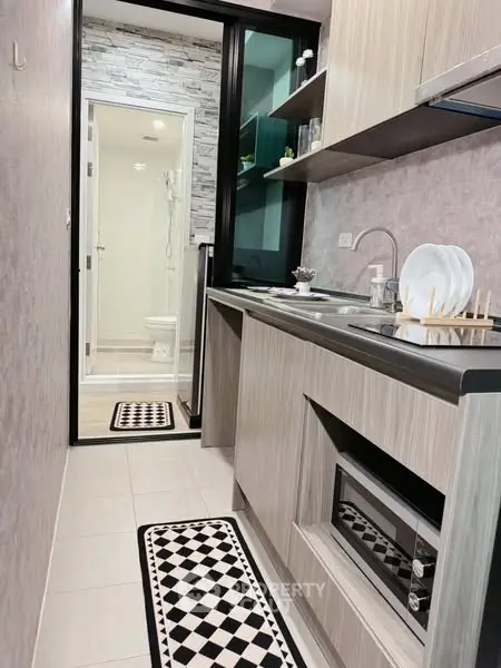 Modern kitchen with sleek cabinetry and built-in oven, leading to a stylish bathroom.