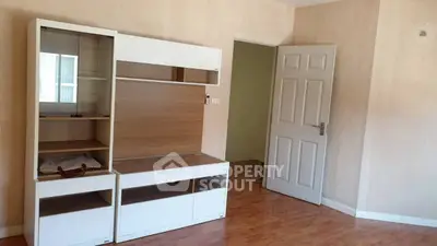 Spacious empty room with wooden flooring and modern shelving unit