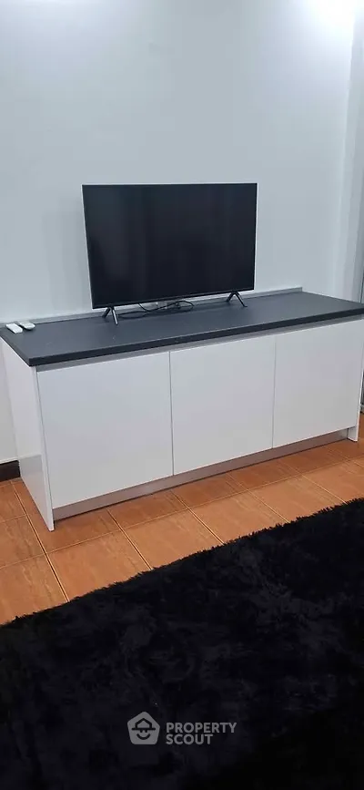 Modern living room with sleek TV stand and flat-screen TV on wooden flooring.