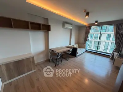 Modern living room with wooden flooring and large windows offering natural light.