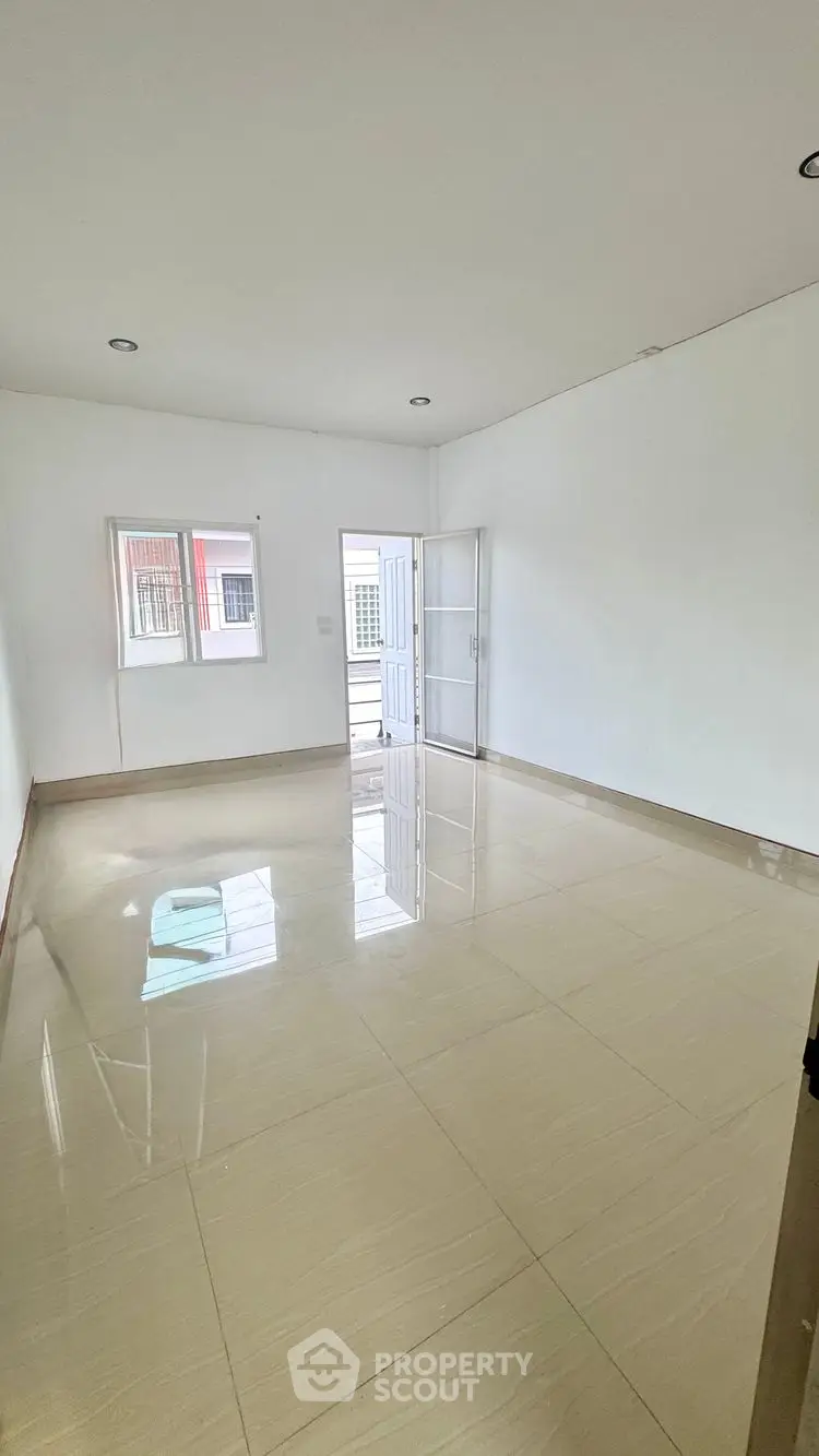 Spacious empty room with glossy tiled floor and natural light