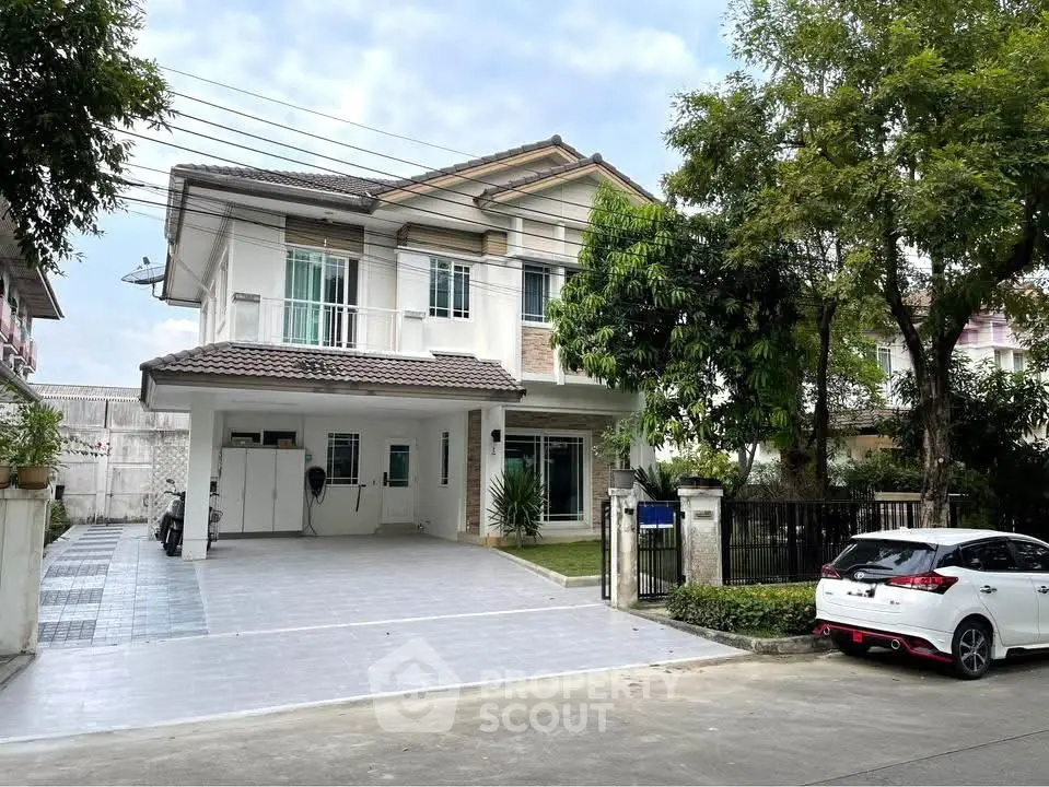 Charming two-story house with spacious driveway and lush greenery in a serene neighborhood.