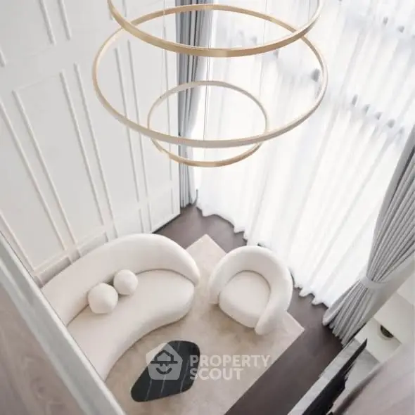 Elegant modern living room with high ceilings, unique circular chandelier, and stylish curved furniture.
