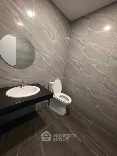 Modern bathroom with sleek gray tiles and round mirror