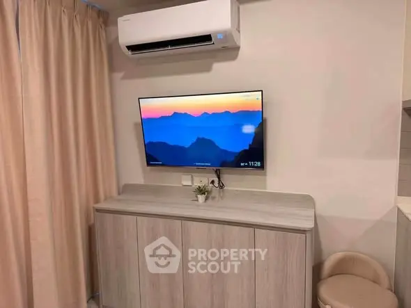 Modern living room with wall-mounted TV and air conditioning unit, featuring stylish cabinetry.