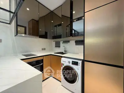 Modern kitchen with sleek cabinetry and built-in appliances, featuring a washing machine and oven.