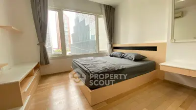 Modern bedroom with large window and city view, featuring sleek wooden flooring and minimalist design.