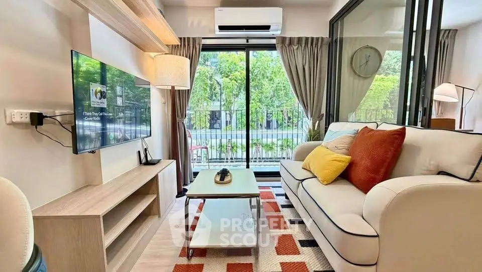 Stylish living room with modern decor, large window, and cozy seating area overlooking lush greenery.