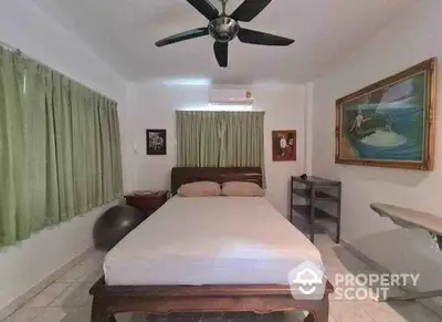 Cozy bedroom with ceiling fan and artwork, featuring green curtains and a wooden bed frame.