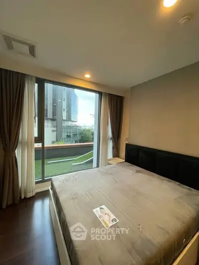 Spacious bedroom with large window offering city view and natural light.