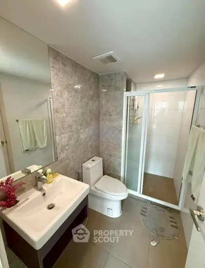 Modern bathroom with sleek fixtures and spacious shower in contemporary apartment.