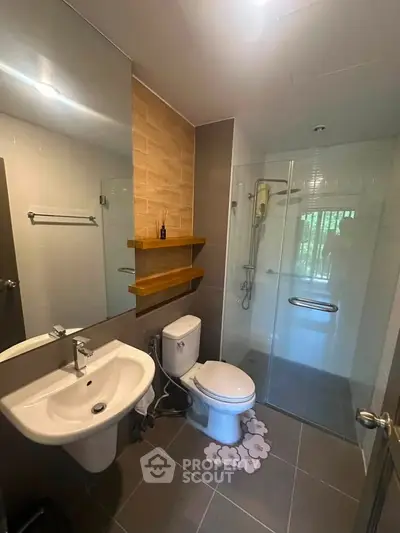Modern bathroom with glass shower, sleek sink, and wooden shelves in a stylish apartment.