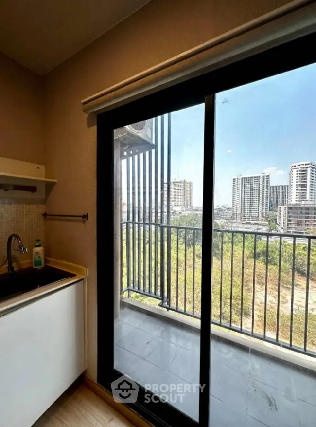 Modern apartment with balcony offering cityscape views through sliding glass doors.
