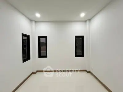 Minimalist empty room with three windows and recessed lighting