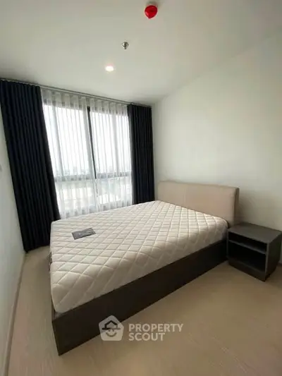 Modern bedroom with large window and minimalist design in a high-rise apartment.