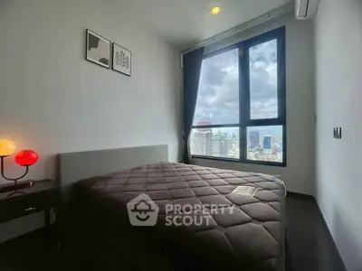 Modern bedroom with large window offering stunning city views, featuring cozy bed and stylish decor.