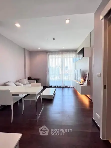 Modern living room with sleek furniture and large window offering natural light.
