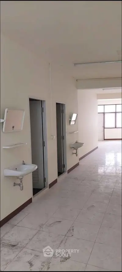 Spacious interior with tiled flooring and multiple sinks, ideal for commercial or residential use.