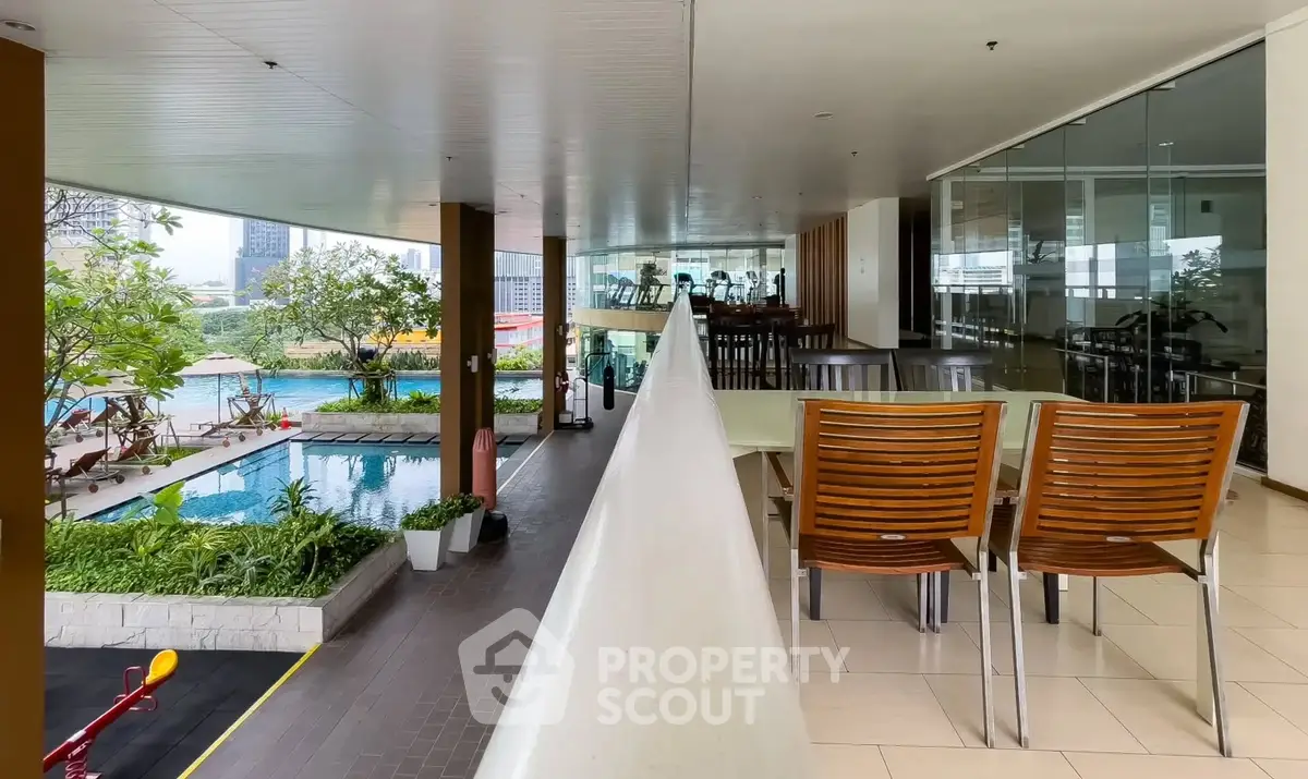 Luxurious poolside view with modern outdoor seating and lush greenery in a high-end residential complex.