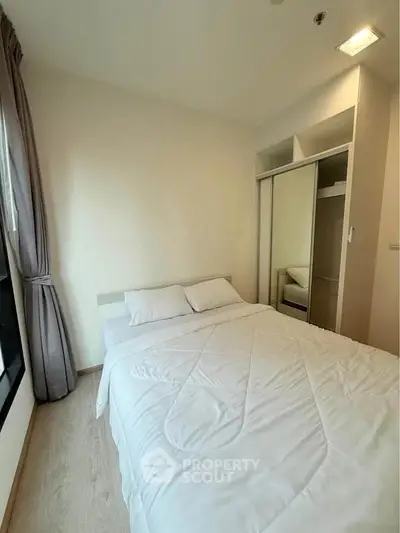Cozy bedroom with large window and built-in wardrobe, perfect for relaxation.