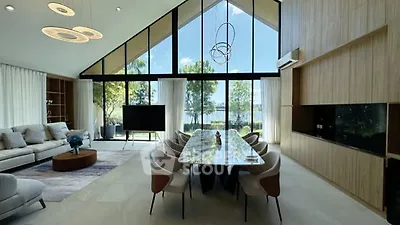 Luxurious modern living room with high ceilings, large windows, and elegant dining area overlooking a scenic view.