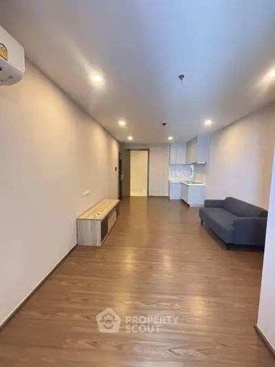 Spacious modern living room with sleek wooden flooring and minimalist furniture.