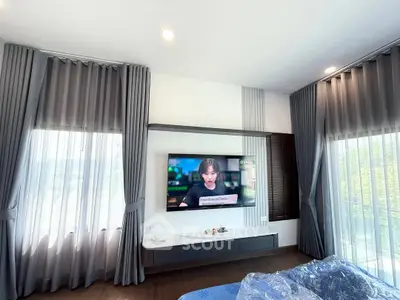 Modern living room with large windows and wall-mounted TV, elegant curtains, and sleek design.