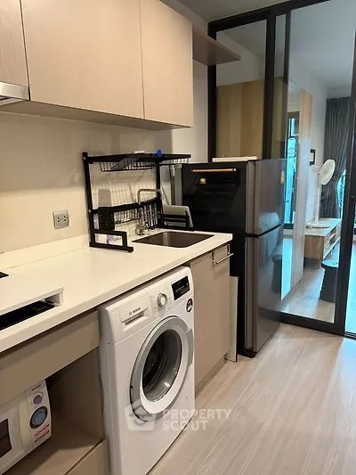 Modern kitchen with washing machine and fridge in sleek apartment