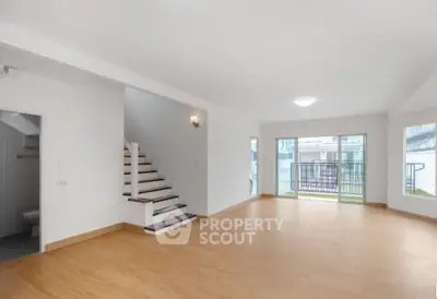 Spacious modern living room with wooden flooring and large windows for natural light.
