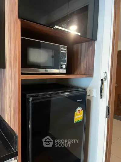 Compact kitchen area with microwave and mini fridge in modern apartment.