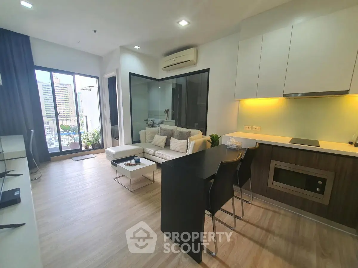 Modern open-layout living room with kitchen, featuring sleek design and city view balcony.