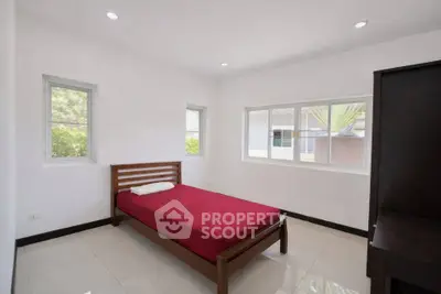 Spacious bedroom with natural light and minimalist design, featuring a single bed and large windows.