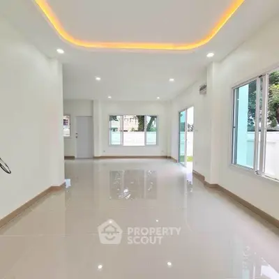 Spacious modern living room with large windows and elegant lighting.